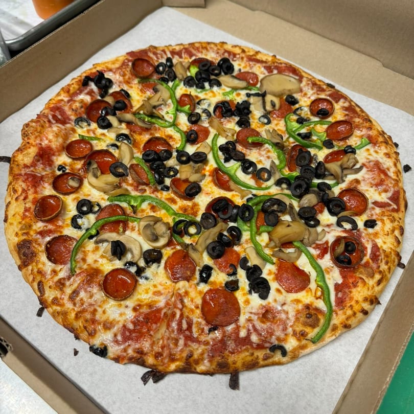 A whole Clarksburg Pizza Co. pizza with pepperoni, mushrooms, black olives, and green peppers.
